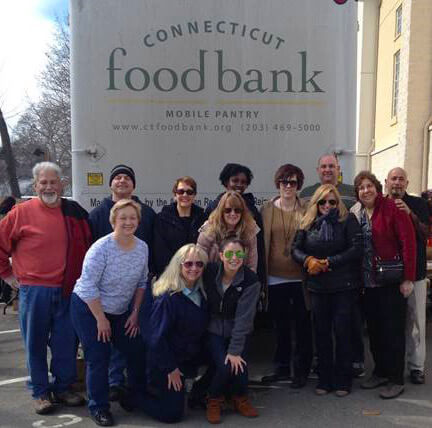 Bedoukian employees gather in front of a sign for the Connecticut Food Bank - one of the many organizations supported by this mission oriented company.